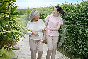 Asian adult daughter hug her senior mother in backyard garden  at home . young woman embrace old mom  to take care in park