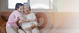 Asian adult daughter hug her senior mother on sofa at home . young woman embrace old mom  to take care on couch in living room .