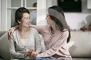 Asian adult daughter and senior mother chatting at home