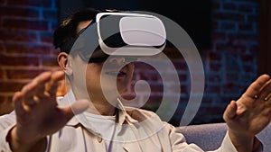 Asian adult man using modern technology explore virtual reality with 3d goggles eyeglasses playing game at night home