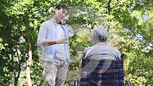 Asian adult son talking to father outdoors