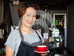 Asian adult waitress holding empty red cup. Concept of keep cleaning cup