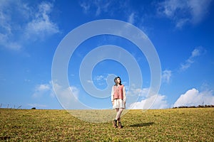 Asian adult woman in dress and long-sleeve with vest happy relaxing in the field with blue sky and clouds a minimal style on natur