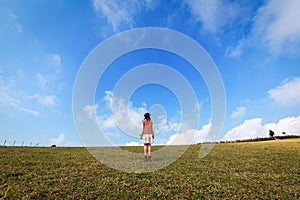 Asian adult woman in dress and long-sleeve with vest happy relaxing in the field with blue sky and clouds a minimal style on natur