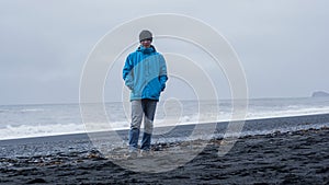 Asian adventure man at Iceland black beach with copy space