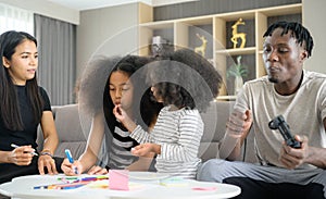 Asian-African American family relaxing, chatting, painting and having fun on vacation