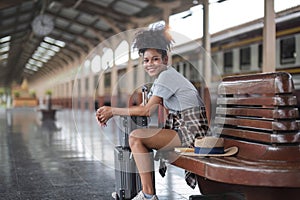 Asian African female tourist traveler holding mobile phone smart phone sitting at train station, Confident smiling