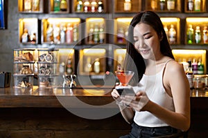 Asian alone women enjoy cocktails in front of a vintage bar, Relaxing activities after work or hangouts