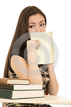 Asian American female student covering mouth with her book