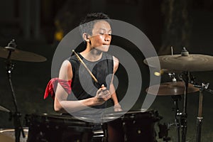 Asian American mixed teenager playing drums at home garden . cool and handsome young boy practicing on drum kit rehearsing