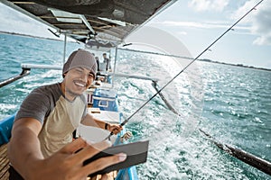 asian angler selfie while fishing with small fishing boat