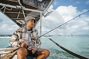 Asian anglers sit with their fishing rods