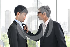 Asian angry boss pulling necktie and yelling at employee, business concept