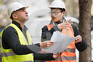 Asian apprentice engineer at work on construction site with the senior manager