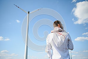 Asian or arabian Engeenier standing against windmills.