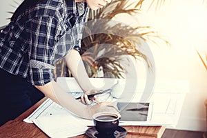 Asian architect woman working at home with tablet and blueprints