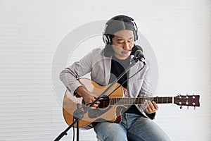 Asian artist singing song and playing acoustic guitar on white background for live acoustic concert and music related concept