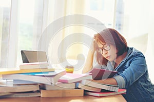 Asian asian women reading something in a book and taking notes at college library.