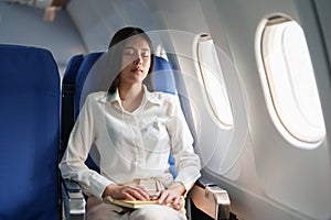 Asian attractive business woman passenger sitting on business class luxury plane while relax while travel concept