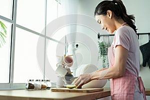 Asian attractive woman wear apron cook green salad in kitchen at home. Young beautiful girl feeling happy and enjoy eating