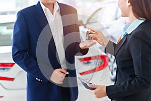 Asian auto business, car sale, deal, gesture and people concept - close up of dealer giving key to new owner in auto showroom