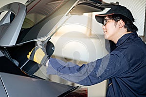 Asian auto mechanic checking car tailgate in garage