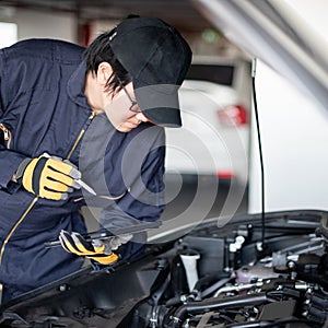 Asian auto mechanic checking the car using tablet