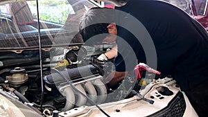 Asian auto mechanic checking and repair engine.