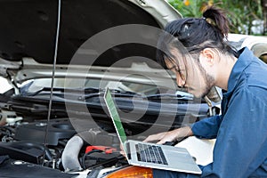 Asian auto mechanic testing car ECU with laptop photo