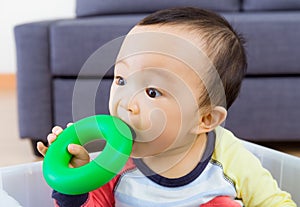 Asian baby boy biting toy