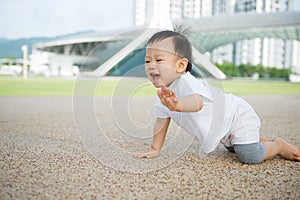 Asian baby boy crawling in park