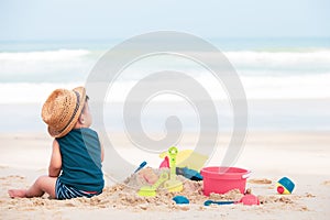 Asian baby boy playing sand on the beach,