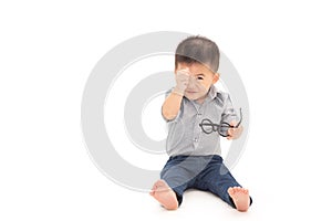 Asian baby boy sit and show mini heart with fingers and wearing business shirt and holding glasses