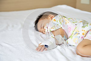 Asian baby boy sleeping on bed with infusion set at child department in the hospital.