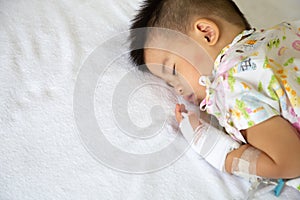 Asian baby boy sleeping on bed with infusion set at child department in the hospital.