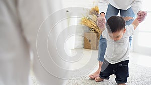 Asian baby boy toddler taking first steps. Family of father and mother encouraging their son learning to walk