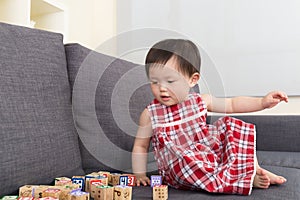 Asian baby girl play toy block and sitting on sofa at home