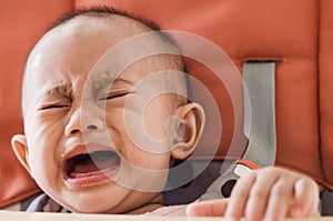 Asian baby girl sitting in highchair and crying refuses to eat f