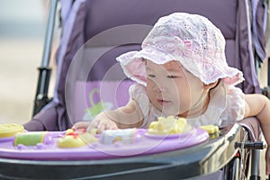 Asian baby girl sitting and playing in stroller on a walk.