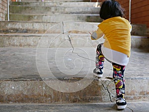 Asian baby girl, 2 years old, learning to climb up the stairs by herself