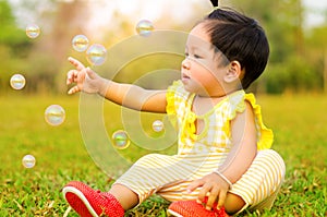 Asian baby happy in grass in moring time with sunlight.