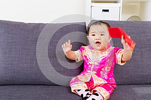 Asian baby holding red pocket with traditional chinese clothing