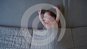 Asian baby infant sleeping on gray bed with blanket. studio shot. baby stretching oneself. kid relaxation.