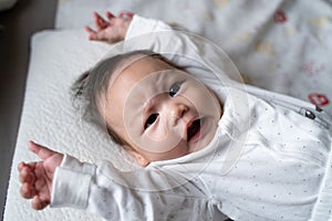 Asian baby infant in white lie down on bed with face expression. facial expression in baby