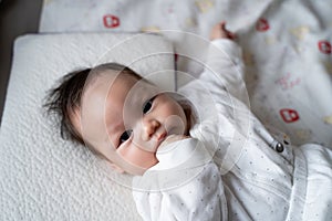 Asian baby infant in white lie down on bed with face expression. facial expression in baby