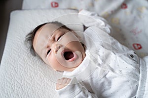 Asian baby infant in white lie down on bed with face expression. facial expression in baby