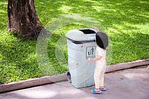 Asian baby little girl throwing garbage into trash can. Baby age 2 - 3 years old.