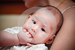 Asian baby put her fingers in mouth.