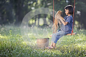 Asian baby on swing with puppy.