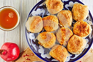 Asian baked meat pies - samsa or sambousak in a national plate with pomegranate, Middle Eastern cuisine on a wooden white table photo